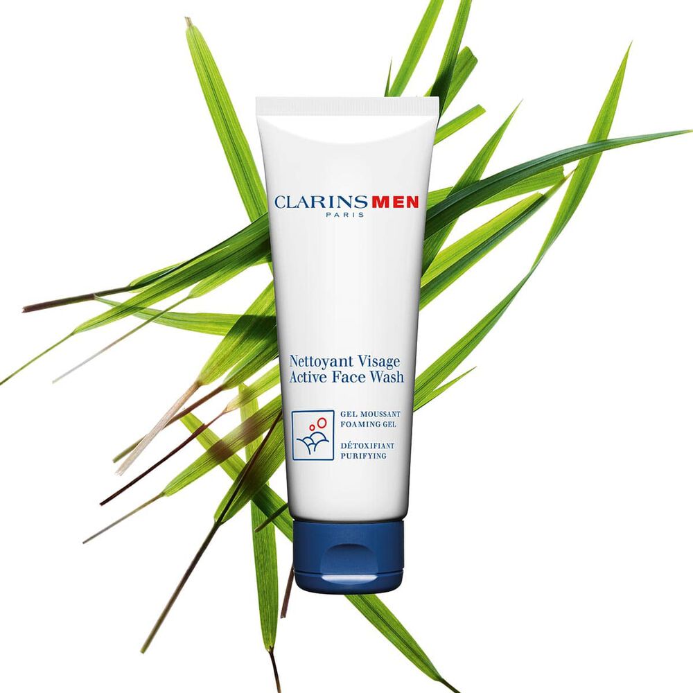 Packshot of the Active Face Wash men's cleanser by Clarins next to bison grass to emphasize its key ingredient.
