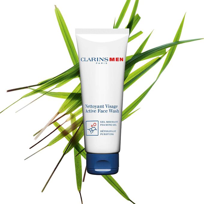 Packshot of the Active Face Wash men's cleanser by Clarins next to bison grass to emphasize its key ingredient.