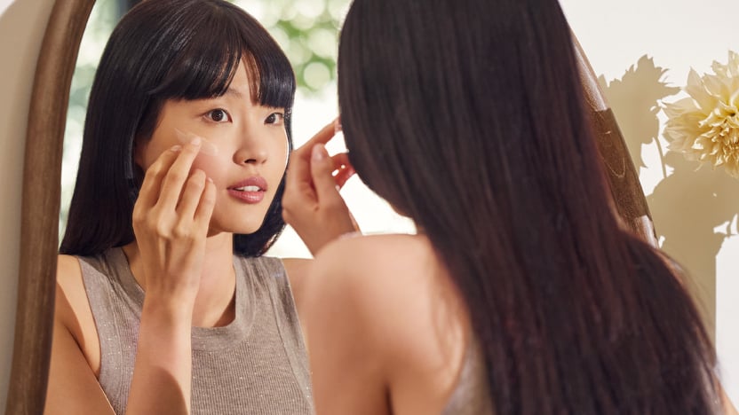 Woman looking at herself in the mirror, exploring Clarins serums designed for every skin type and concern.
