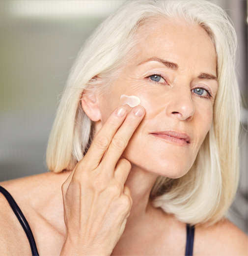 A mature woman applying facial cream